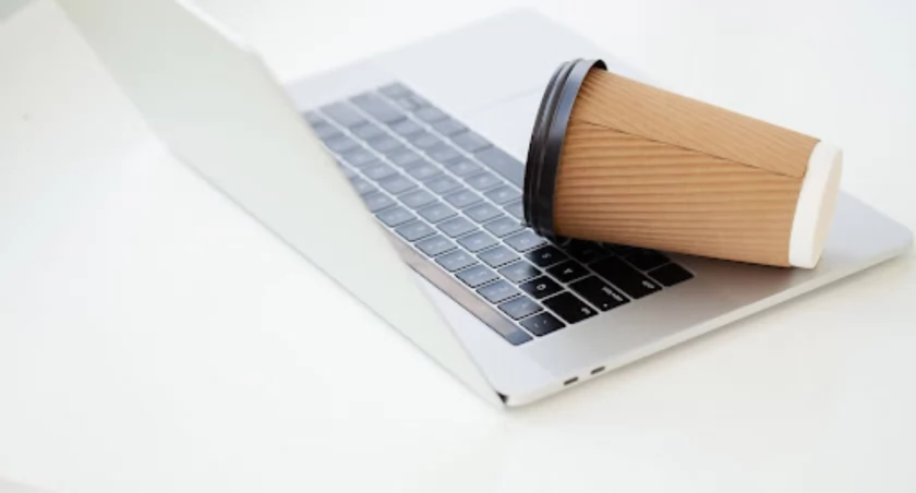 kubek z kawą leżący na otwartym laptopie